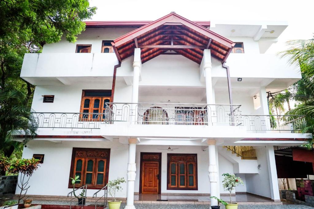 SATK INN Jaffna, Kokkuvil的白色的房子,设有橙色门和阳台