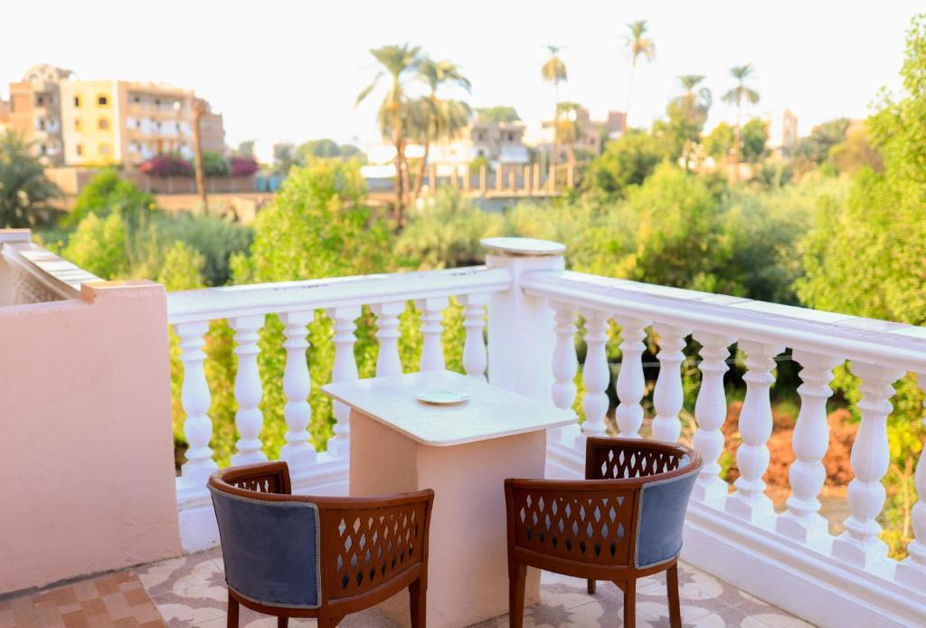 卢克索Luxor Nile View Flats的阳台配有两把椅子和一张桌子,位于栏杆上