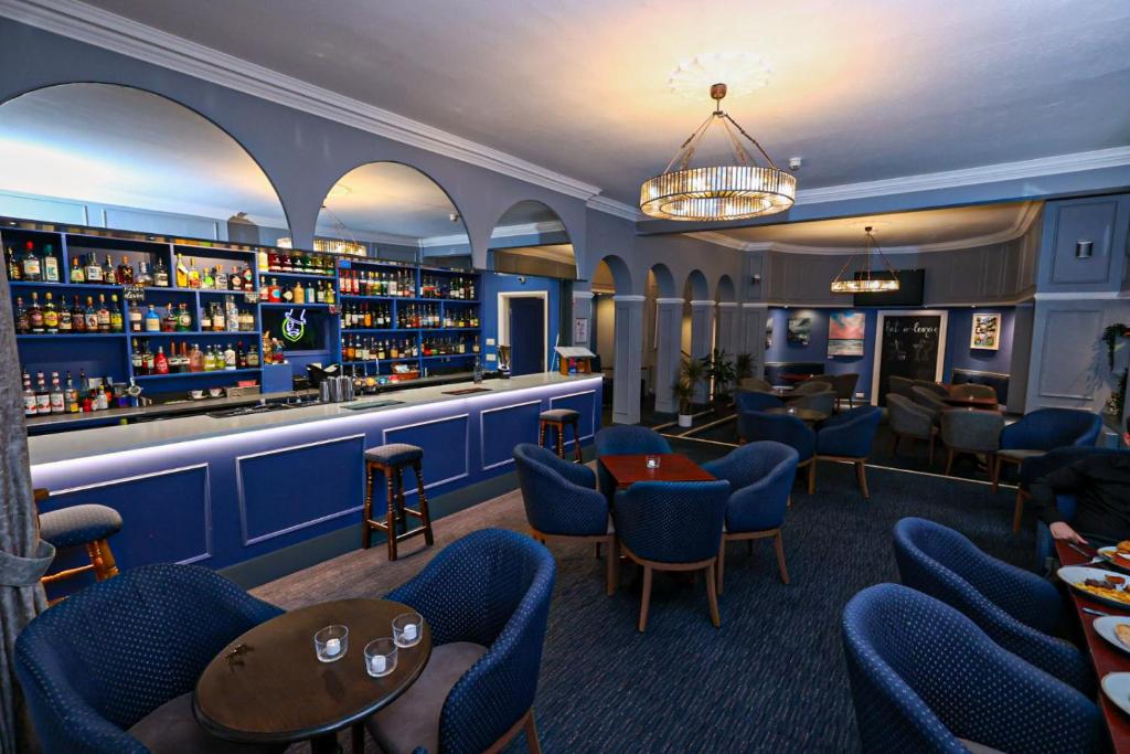 埃克斯茅斯庄园酒店的餐厅内的酒吧,配有蓝色的椅子和架子