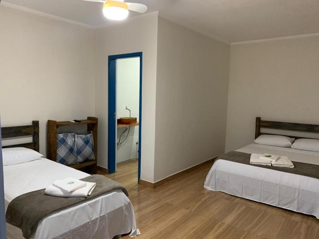 塞拉内格拉Pousada Fazendinha Alto da Serra的客房设有两张床和一间带镜子的浴室
