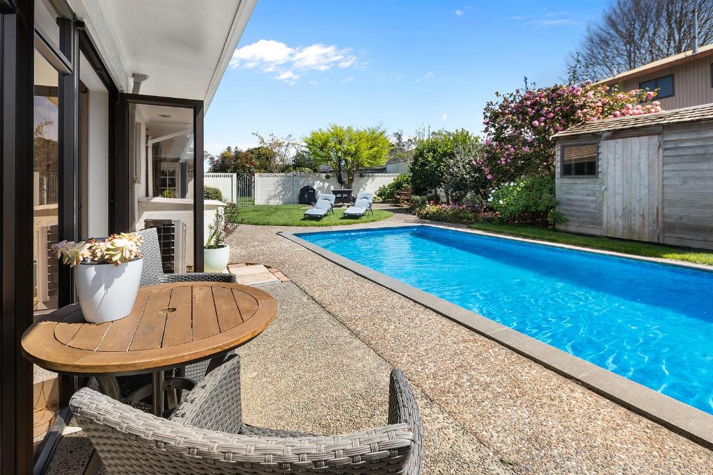 汉密尔顿Hamilton Summer Treat- 4 Bedroom with pool的房屋旁的游泳池配有桌椅