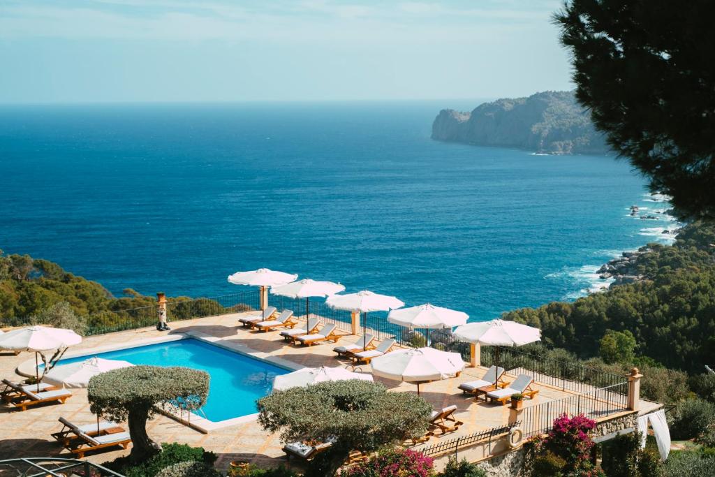 德阿萨佩德利萨酒店的一个带遮阳伞和椅子的游泳池以及大海