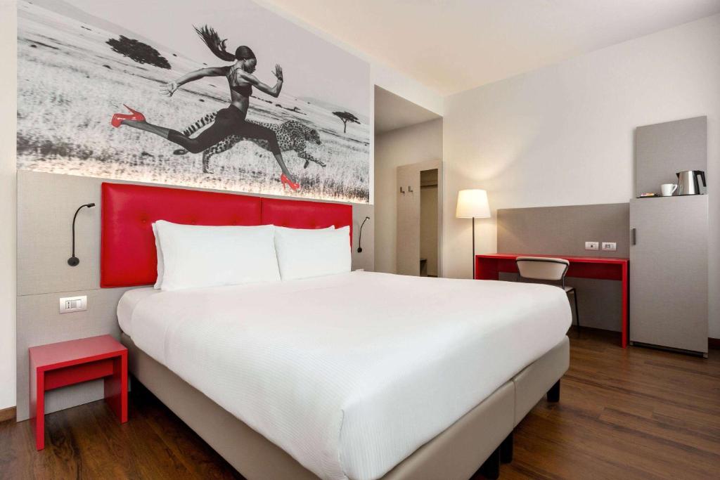 米兰Amedia Milano, Trademark Collection by Wyndham的酒店客房设有一张大床和红色床头板