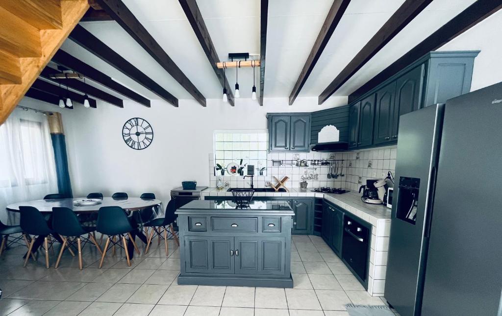 珀蒂蒂勒Villa Longani Passion pour des vacances bucoliques en famille的厨房配有绿色橱柜和桌椅