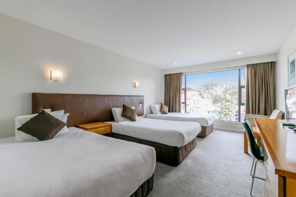奥克兰Boulevard Hotel的酒店客房设有两张床和窗户。