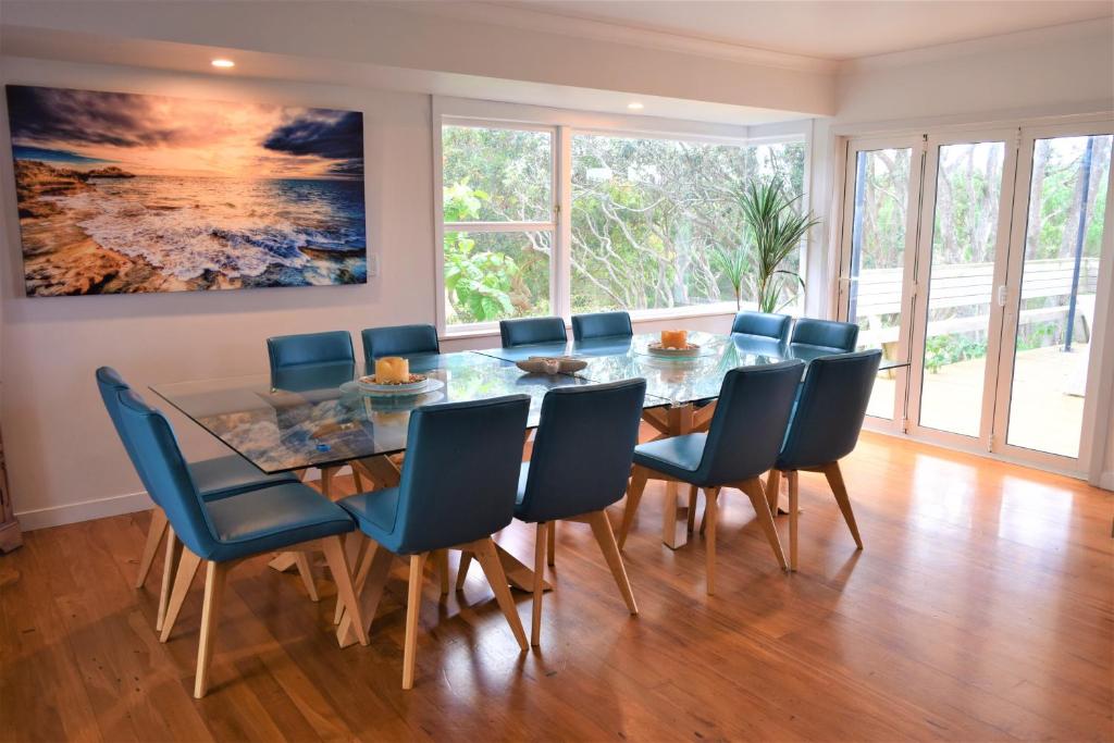 KaihuKai Iwi Lakes Resort的一间设有玻璃桌和蓝色椅子的用餐室