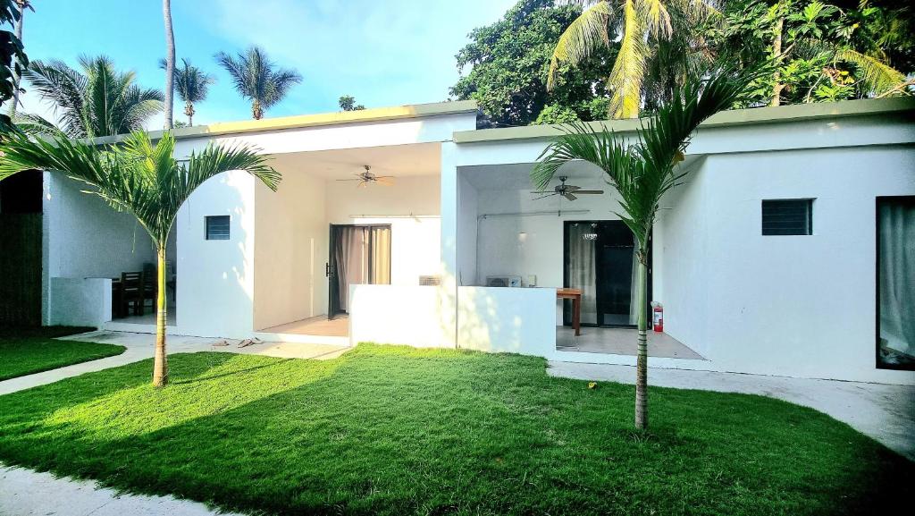 PoocTiki Bantayan Cebu Tourist Inn Inc的院子里两棵棕榈树的白色房子