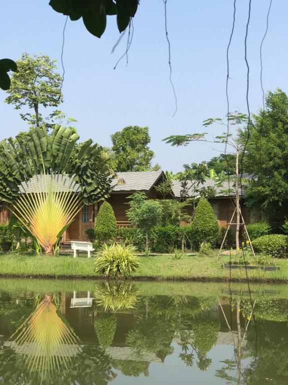 巴吞他尼Sripiamsuk Resort Bangkok的前面有池塘的房子