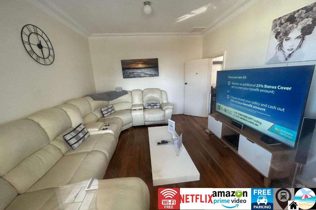 卧龙岗Wollongong station holiday house with Wi-Fi,75 Inch TV, Netflix,Parking,Beach的客厅配有大沙发和平面电视