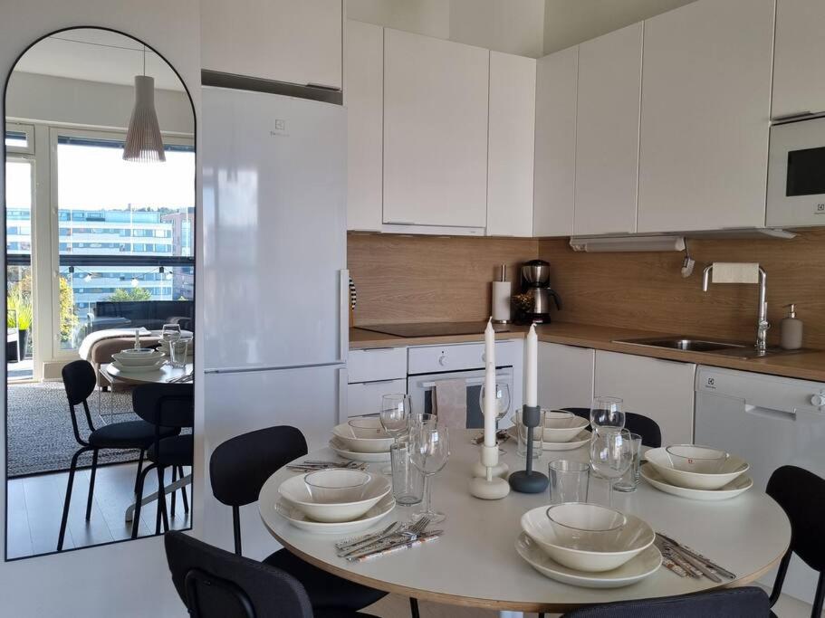 坦佩雷Hotellitasoinen, uusi huoneisto!的厨房配有桌椅和白色橱柜。