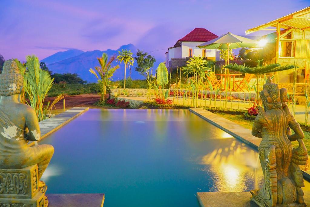 金塔马尼Pondok Bali Cottage的一座房子前面带两座雕像的游泳池