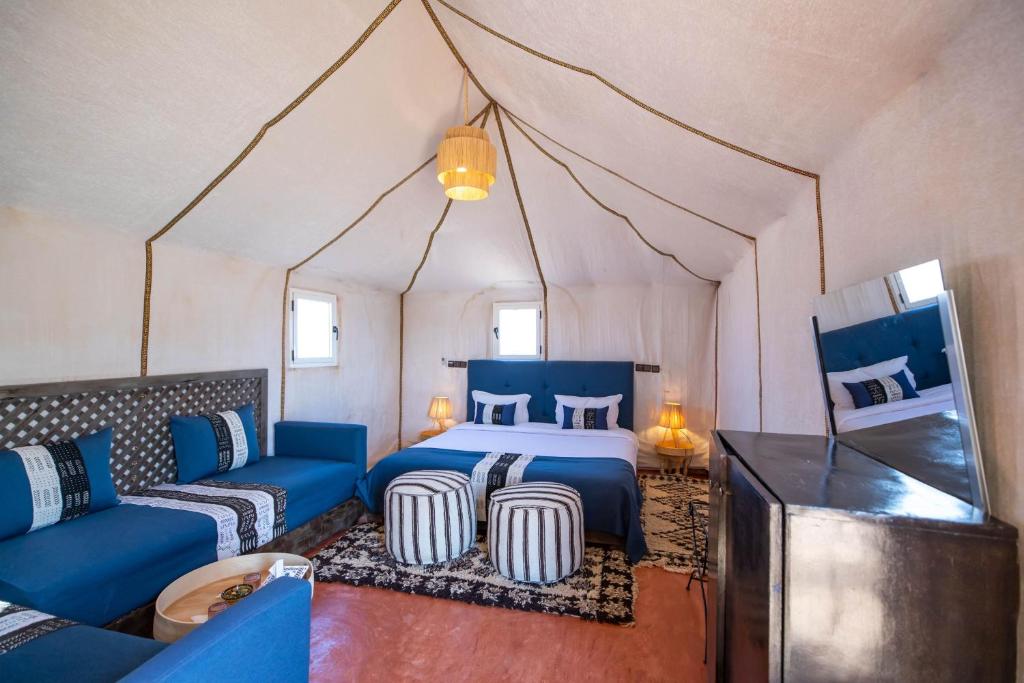 梅尔祖卡Golden Camp & Oasis的一间卧室配有一张床,一张沙发位于帐篷内