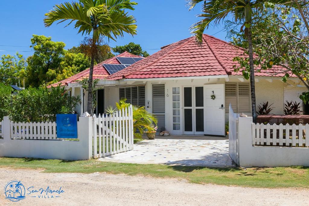 银沙Sea Miracle Villa/Beach Cottage的白色围栏和棕榈树的房子