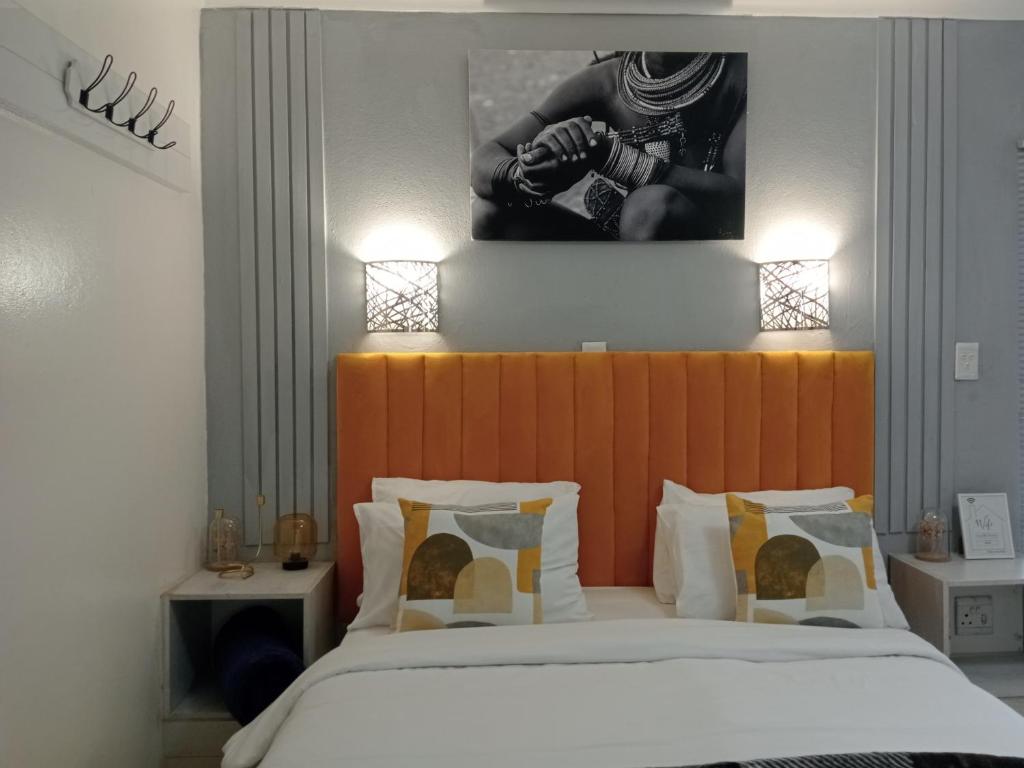 肯普顿帕克Aneiwa airport lodge的一间卧室配有一张带橙色床头板的大床