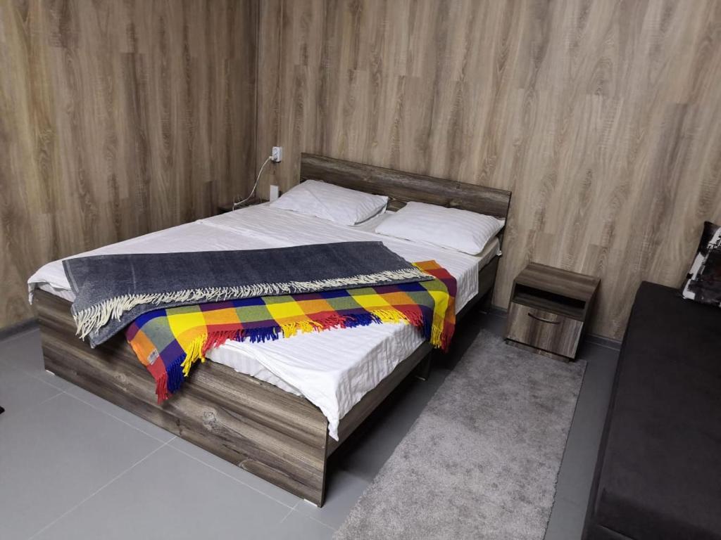 阿拉木图The Mini-hotel on Mukanova St的一间卧室配有一张带彩色毯子的木床
