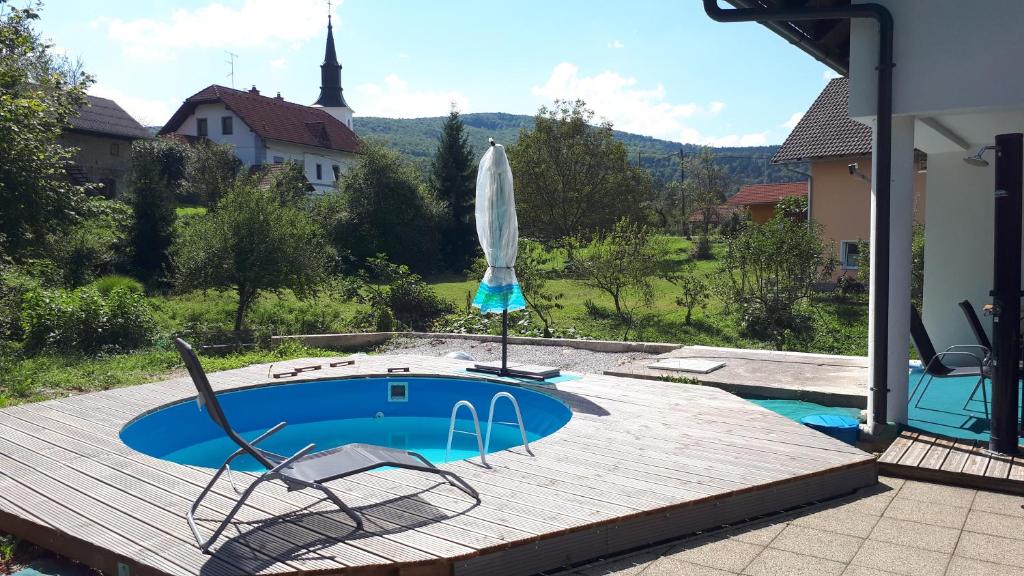 Uršna SelaLepa Dolenjska的木制甲板上配有椅子和遮阳伞的游泳池