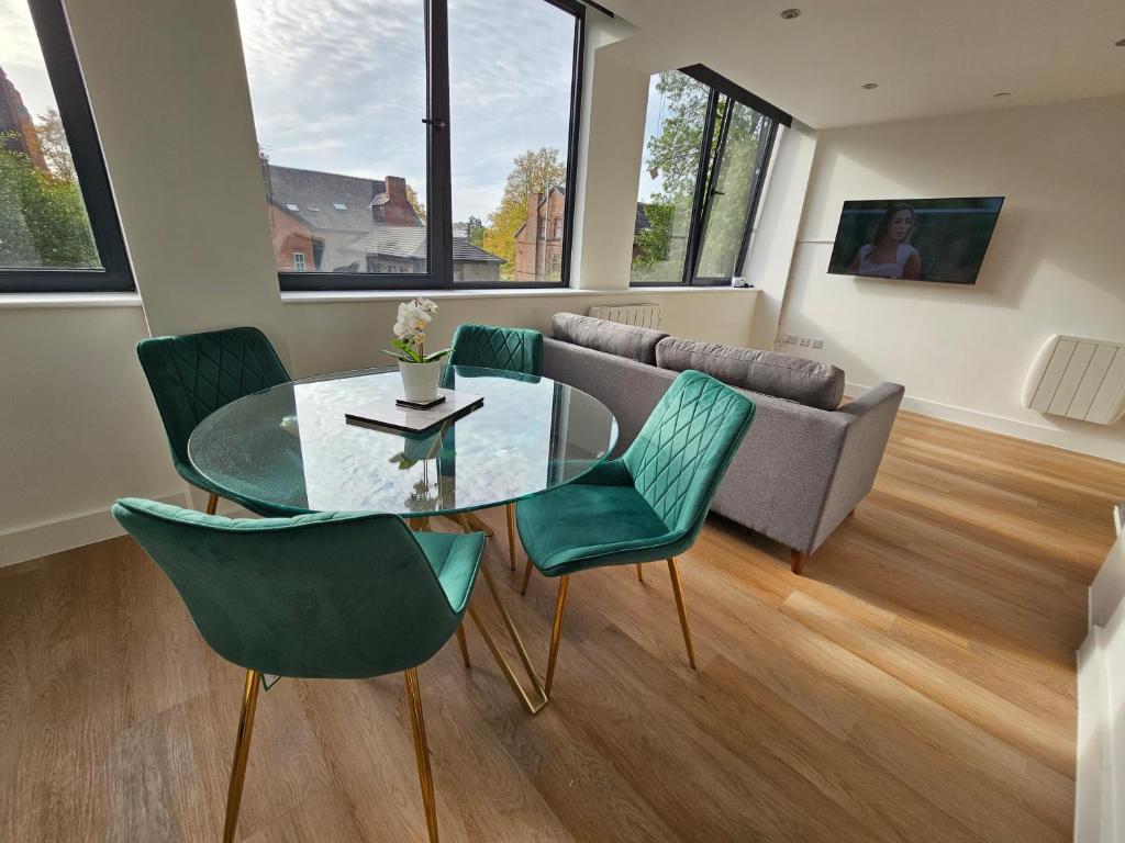 曼彻斯特Brand New Trafford Apartment的客厅配有玻璃桌和绿色椅子