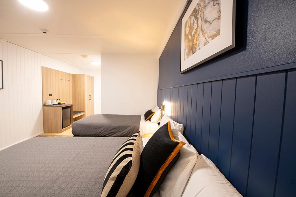 悉尼Southend Hotel的一间卧室设有两张床和蓝色的墙壁