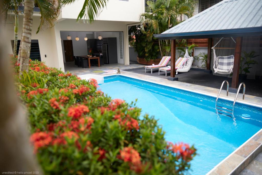 帕拉马里博Tropical Villa Rainville的一座房子旁的游泳池,里面摆放着椅子和鲜花