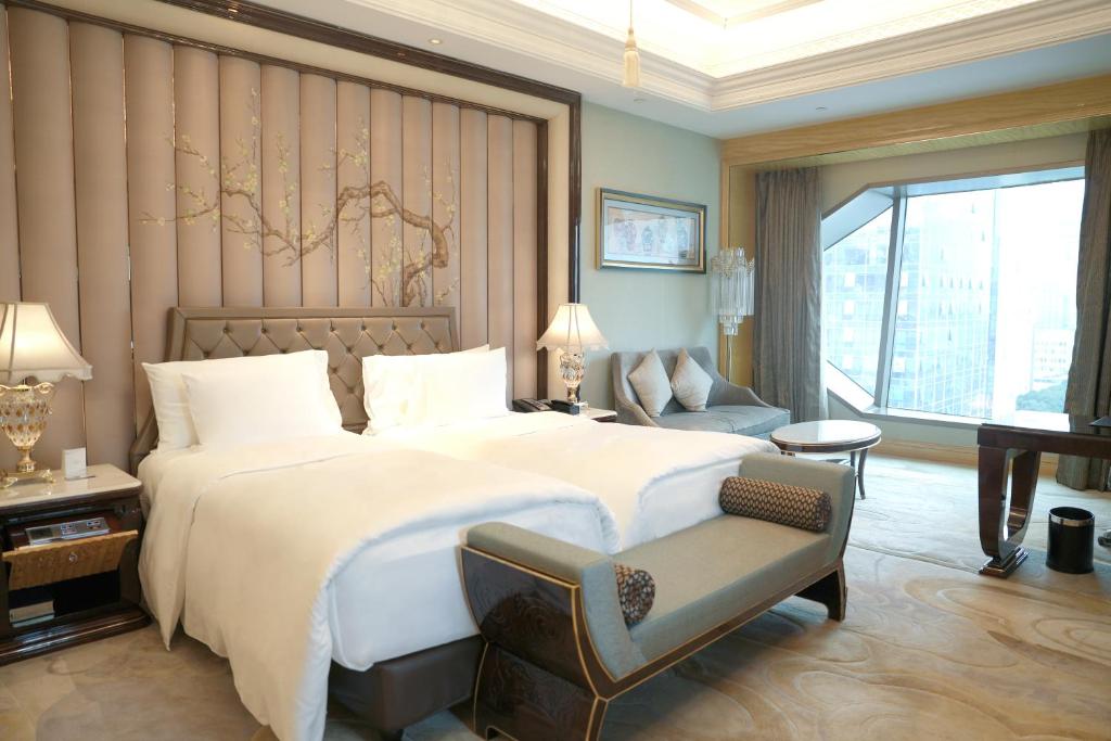 武汉武汉万达瑞华酒店的卧室配有一张白色大床和一把椅子