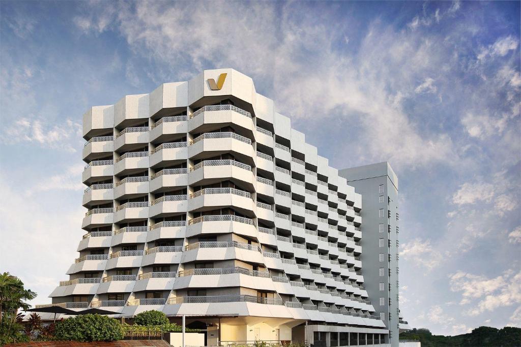 新加坡Village Hotel Katong by Far East Hospitality的一座高大的白色建筑,上面有金色的标志