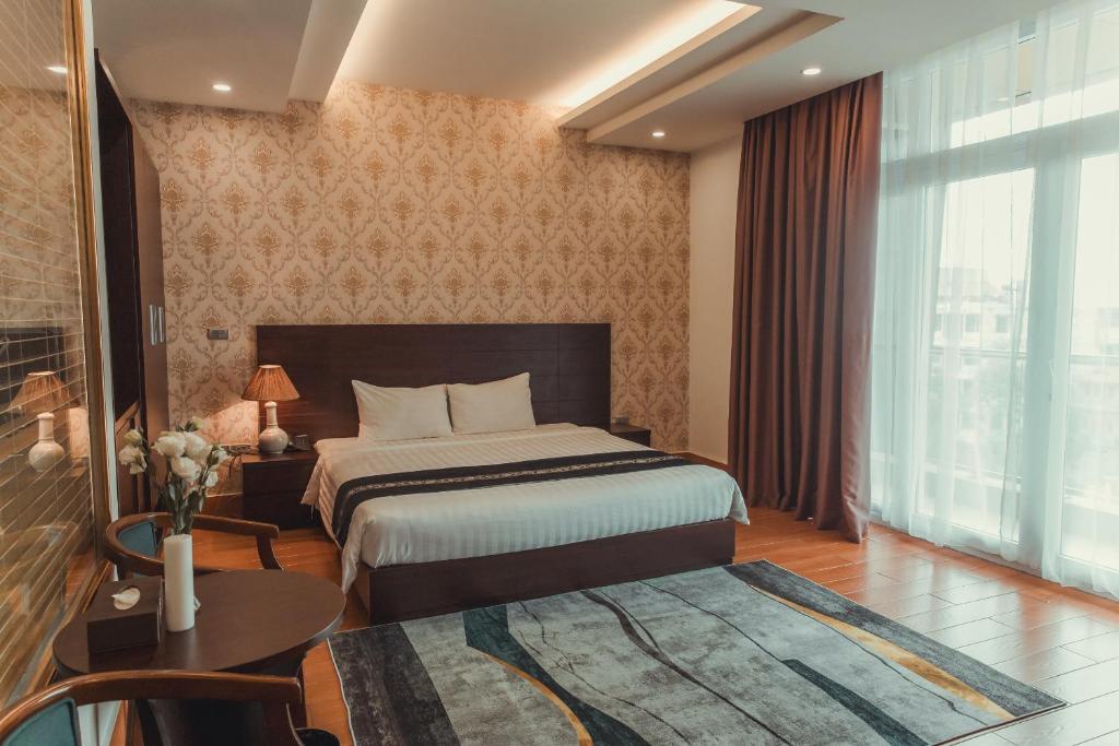 北宁J&C HOTEL的一间卧室配有一张床、一张桌子和一个窗户。