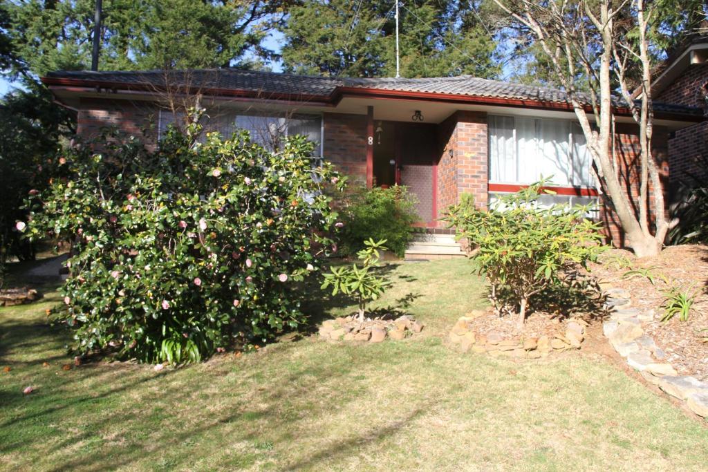 卢拉Azalea Cottage, Leura NSW Australia的院子里有花丛的房子
