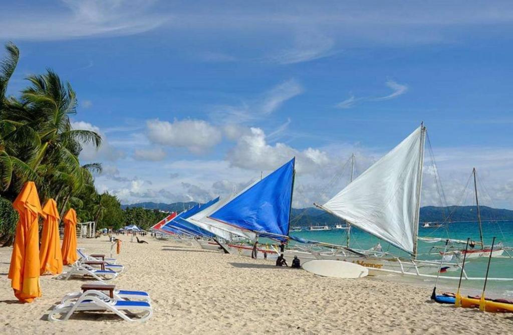 长滩岛8 Colors Penthouse Boracay Beach House Resort by Cocotel的沙滩上有许多帆船