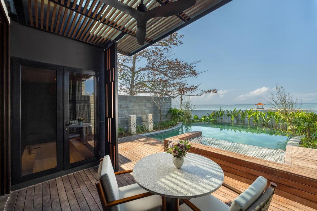 沙努尔Sumitra Luxury Villas A Pramana Experience的一个带桌椅的庭院和一个游泳池