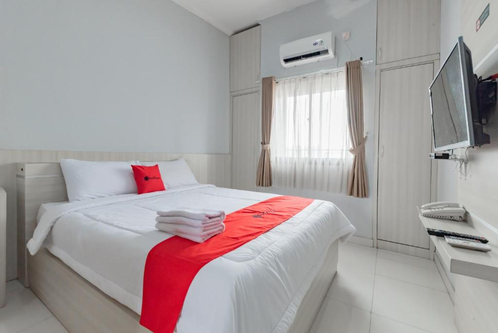 万隆RedDoorz near Stadium Arcamanik Bandung的一间白色卧室,床上铺有红色毯子