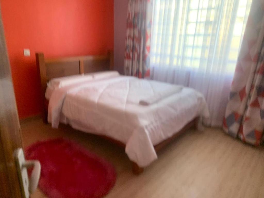 Kitengela Happy home from home的一间卧室设有一张床和红色的墙壁