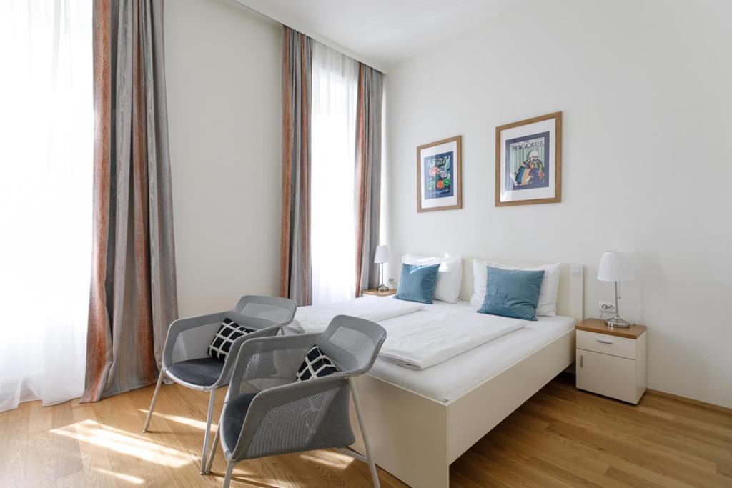 维也纳Riess City Rooms - Self Check-in的一间白色卧室,配有一张床和两把椅子