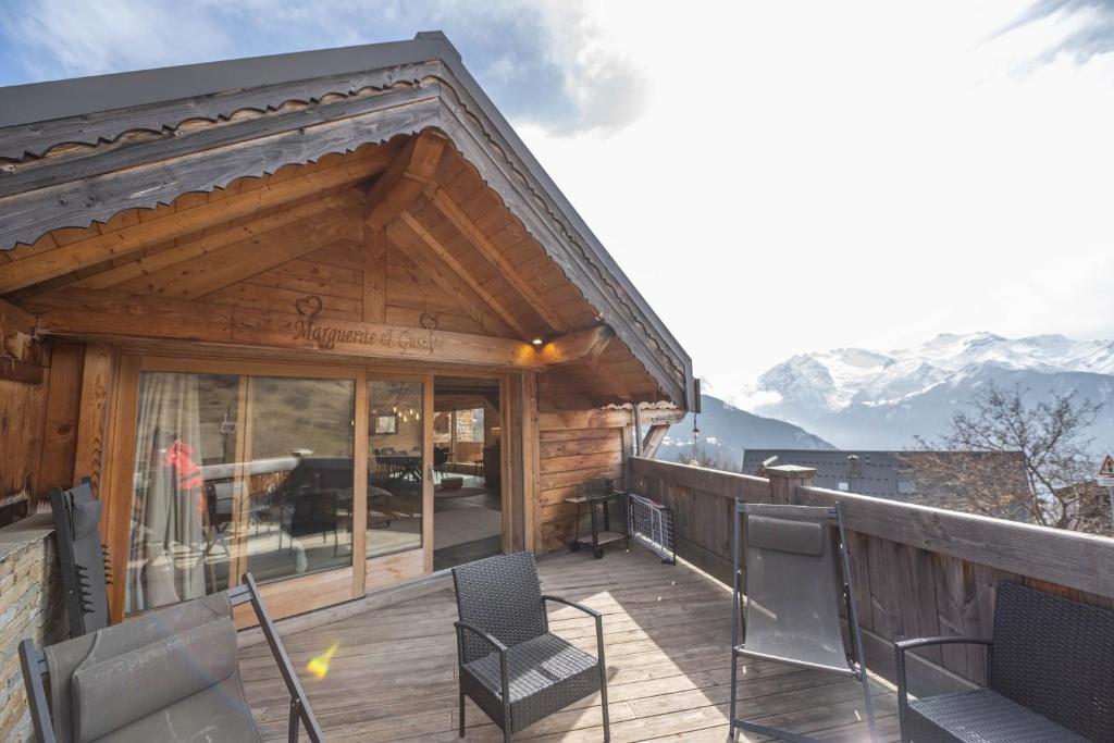 于埃Beau chalet GUSTAVE 4 chambres 50m piste Huez Express的一个带椅子的木制甲板和一座享有山景的建筑