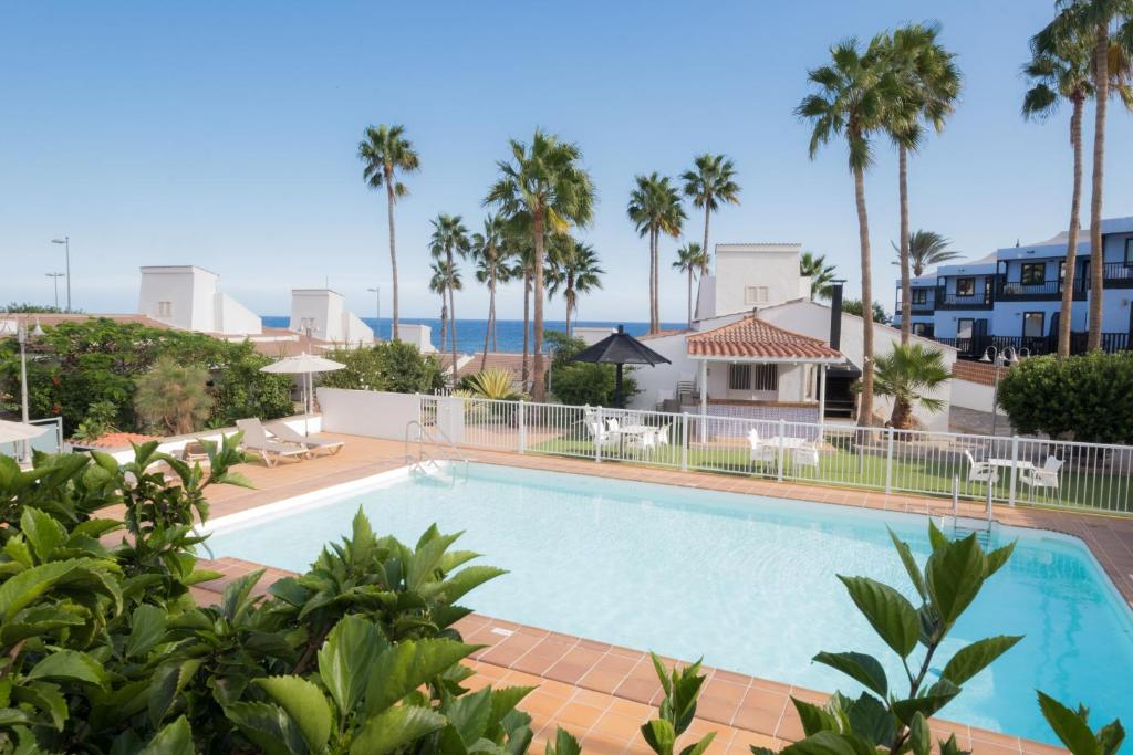 阿吉拉海滩MAKĀI Bungalows的一座棕榈树游泳池和一座房子