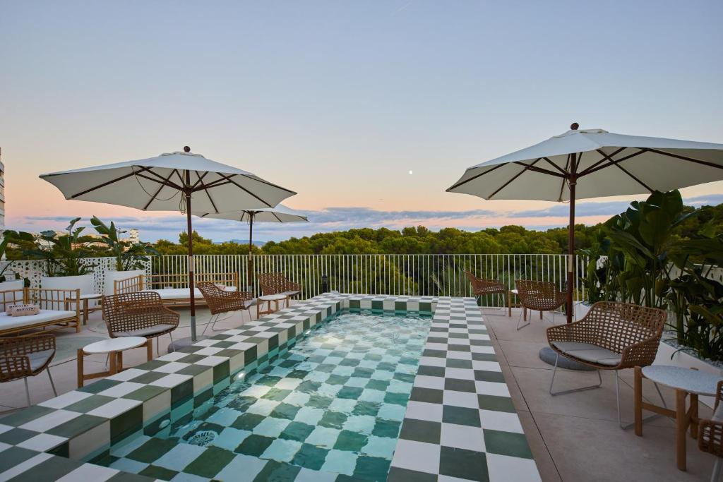 马略卡岛帕尔马Belle Marivent Mediterranean Petit Hotel的一个带桌椅和遮阳伞的游泳池