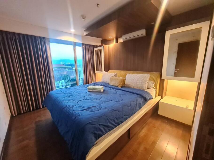 万隆2BR El Royale Apartement Braga的一间卧室设有蓝色的床和窗户。
