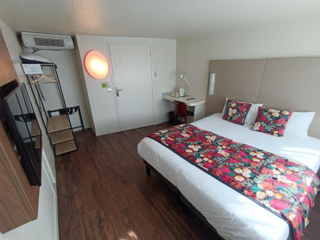 坎佩尔Brit Hotel Quimper Sud的酒店客房,配有一张带花卉图案的床铺