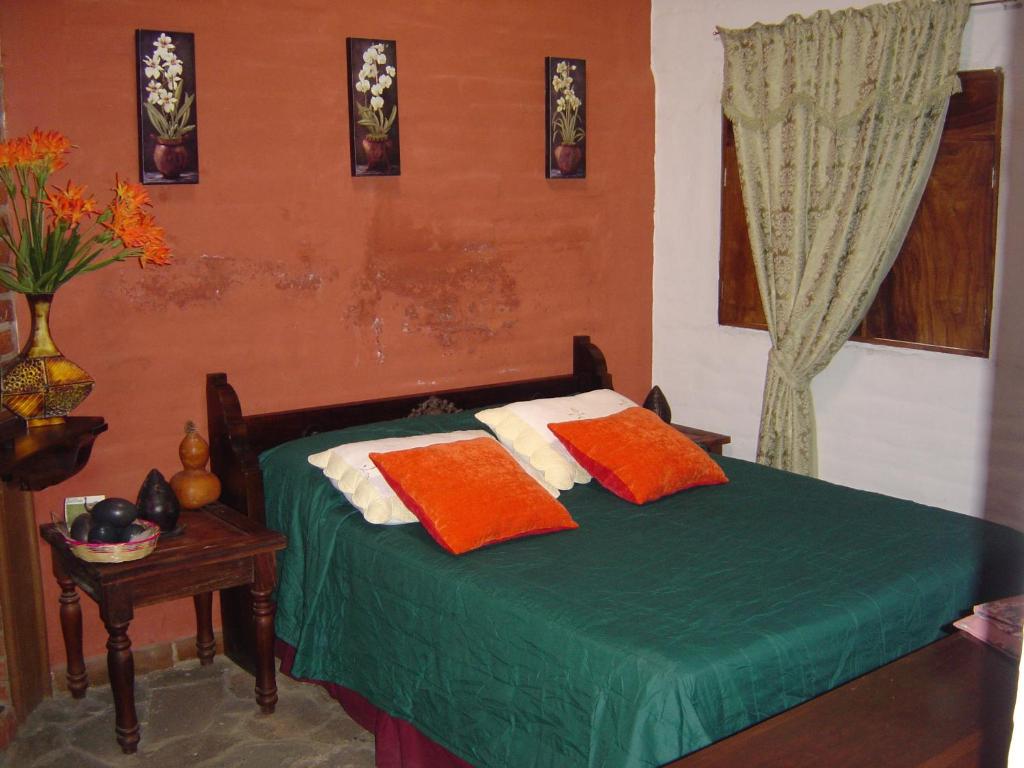 康塞普西翁德阿塔科圣多明各别墅酒店的一间卧室配有绿色的床和橙色和白色枕头