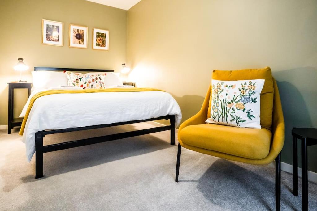 莱斯特Artist's Garden on Wolsey Island的一间卧室配有一张床和一张黄色椅子