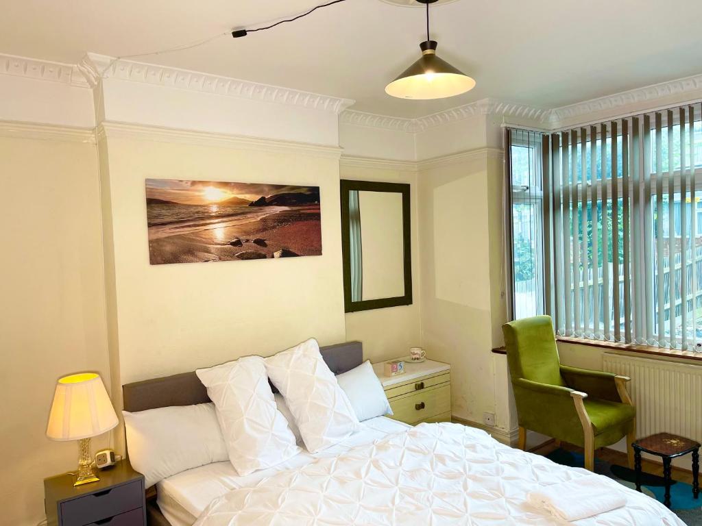 South NorwoodE-Sky Homes的卧室配有白色的床和绿色椅子