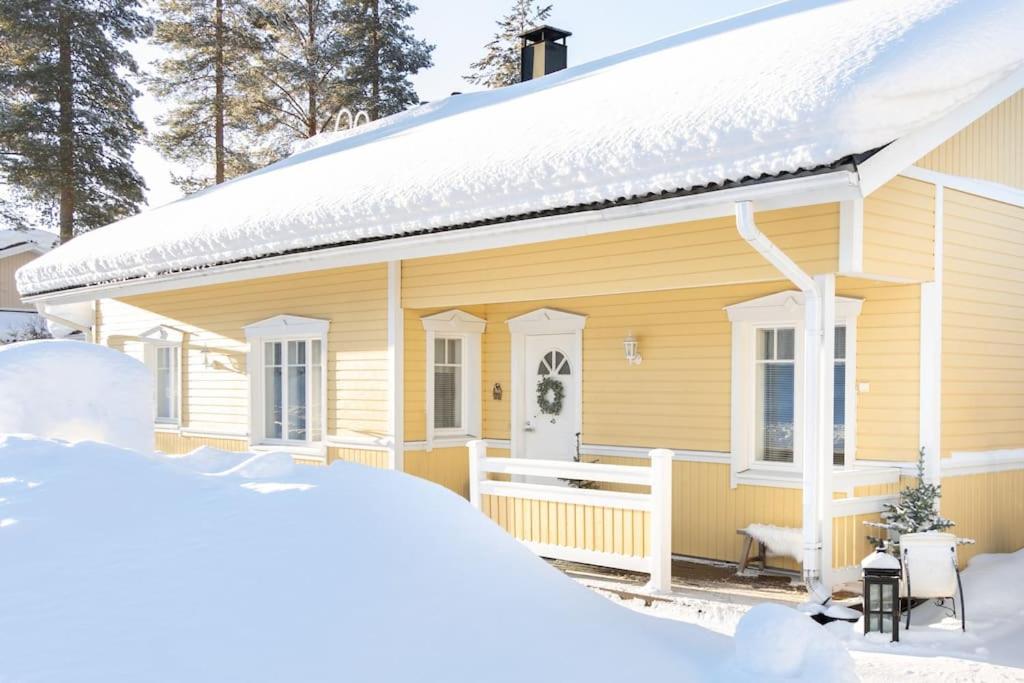 罗瓦涅米Arctic Circle Home close to Santa`s Village的前面有雪的黄色房子
