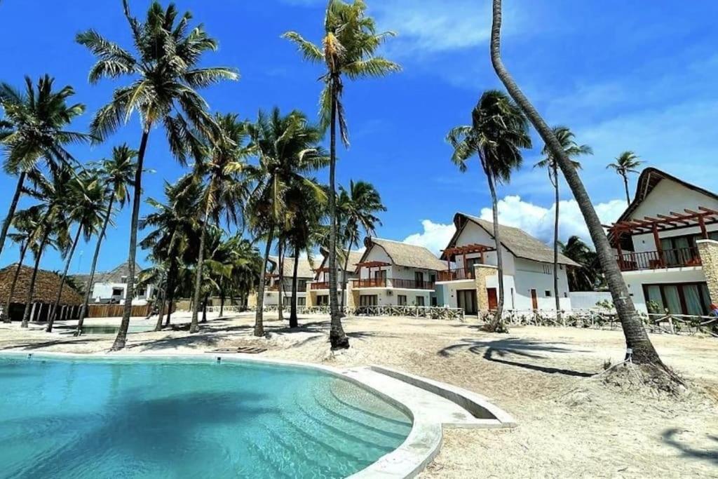 平圭Ocean Front Villa with pool, Zanzibar的一个带游泳池和棕榈树的度假村