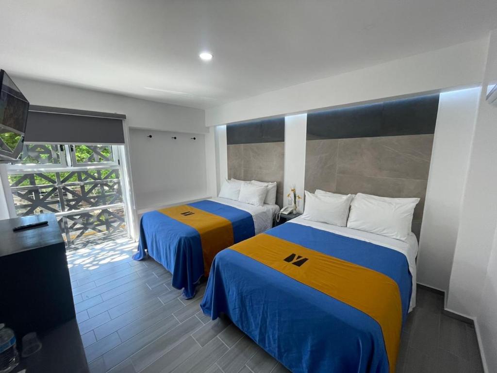 韦拉克鲁斯Hotel GALENO的一间卧室设有两张蓝色和黄色的床