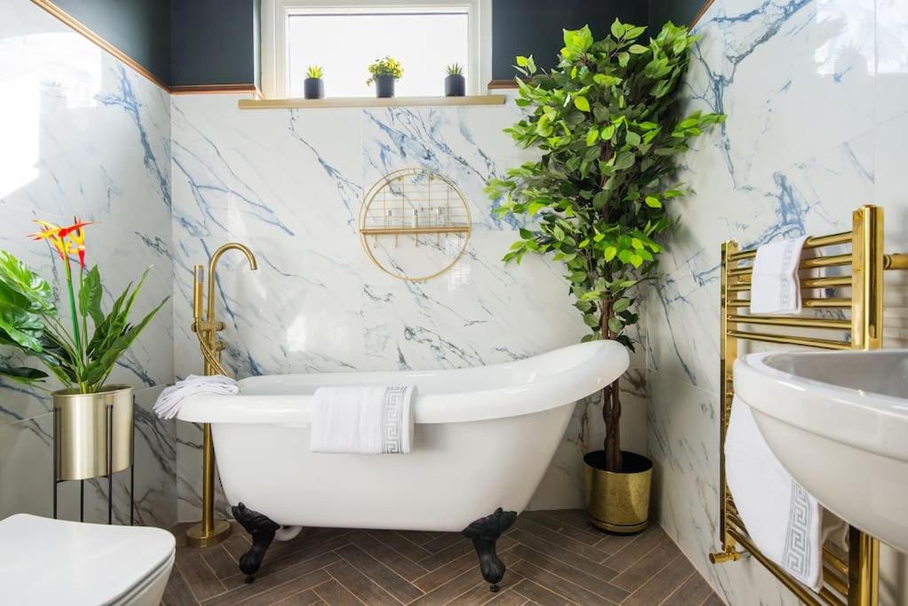伦敦Lux Versace Pad Sleeps 10 Hot Tub, Cinema & Games Room的浴室配有白色浴缸和水槽