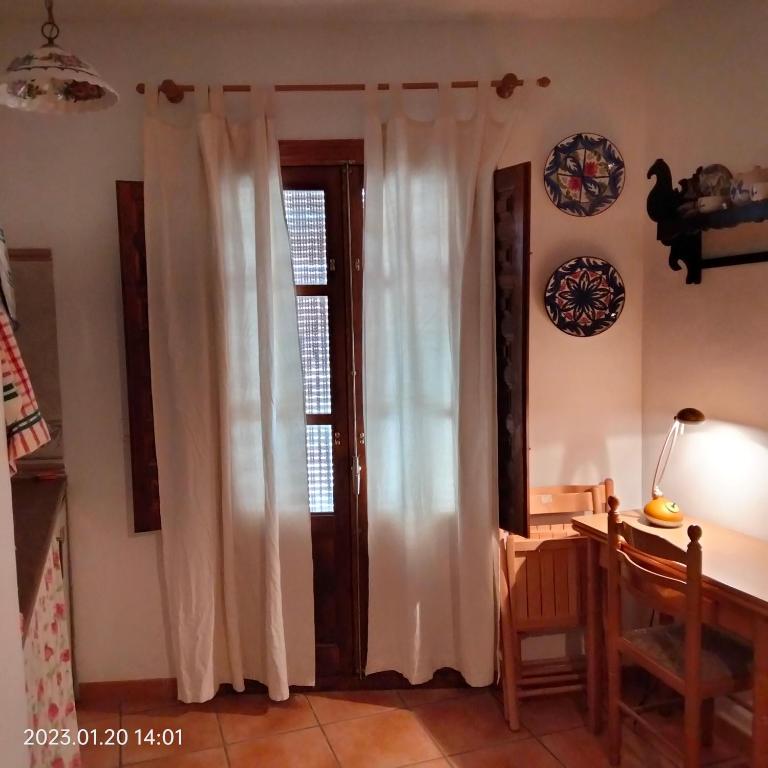 拉洛勒斯Apartamento vacacional en la Alpujarra的客房设有带白色窗帘和桌子的窗户。