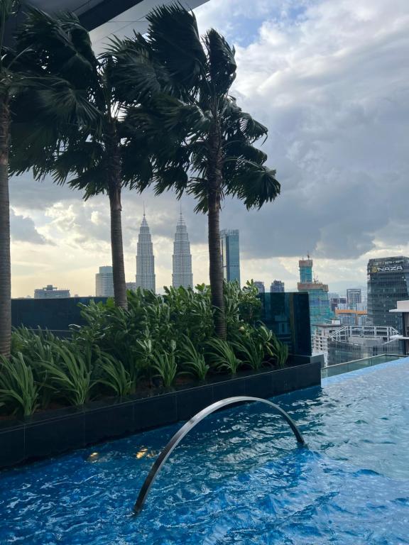 吉隆坡Eaton Residence KLCC BY Galaxy Suites的棕榈树建筑屋顶上的游泳池
