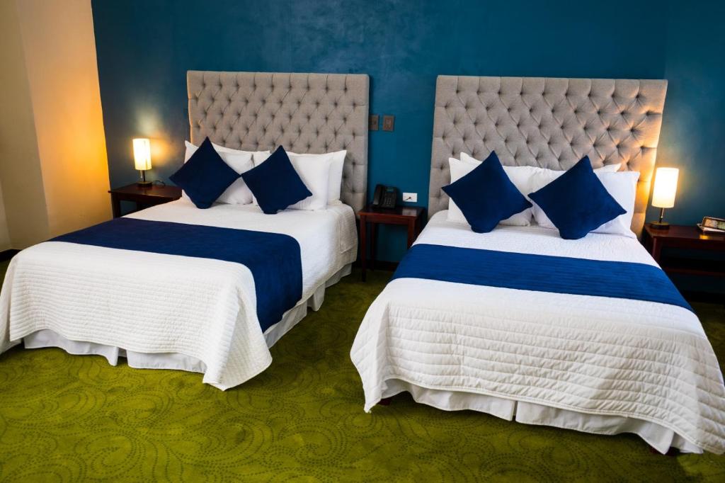 普埃布拉HOTEL MARGARITA的两张位于酒店客房的床,拥有蓝色的墙壁