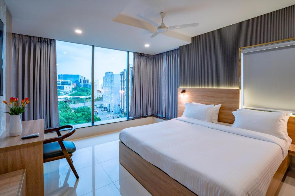 海得拉巴Harvey's Hotels (Gachibowli)的一间卧室配有一张床、一张书桌和一个大窗户