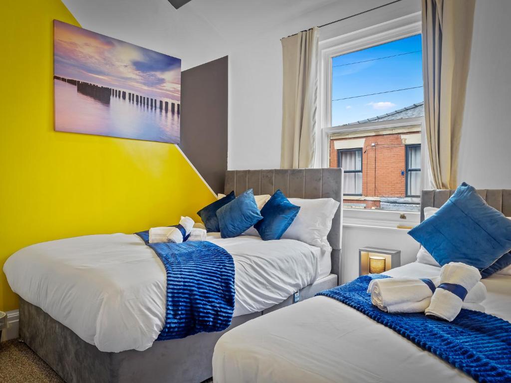 普雷斯顿Preston Serviced Apartment - Estatevision的一间卧室配有两张带蓝白色枕头的床
