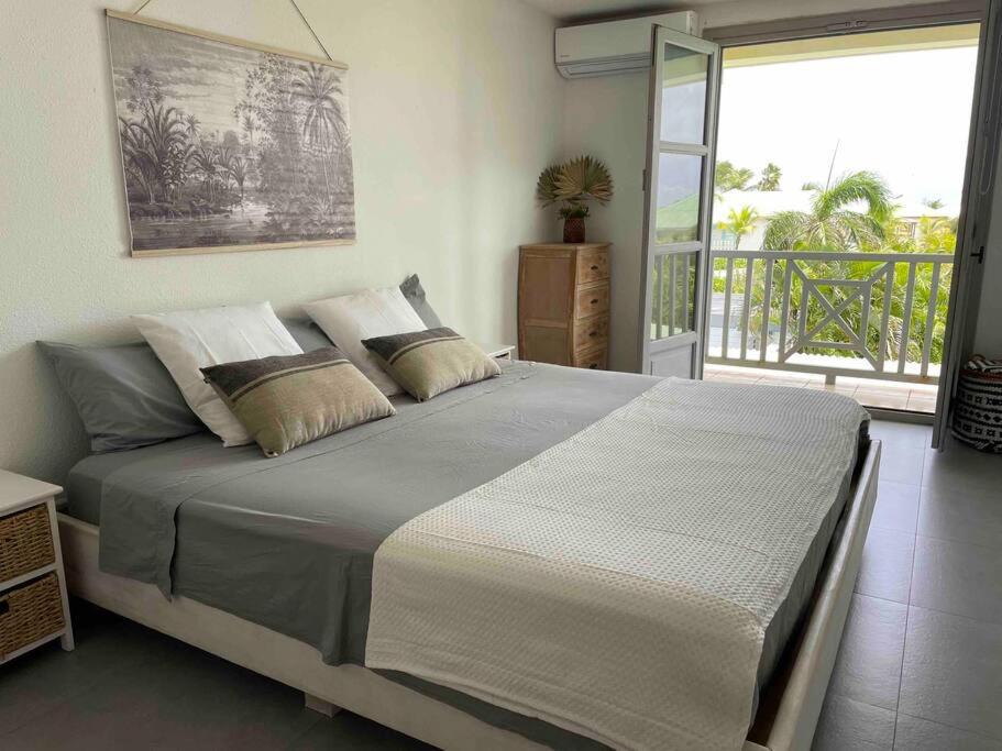 Saint MartinOrient Bay villa的一间带大床的卧室和一个阳台
